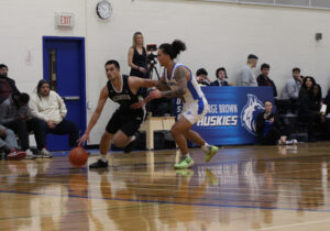Algonquin Wolves men's basketball guard Albert Opena dribbles against Dylan Jones of the George Brown Huskies.