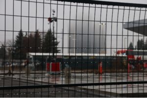a close shot of the construction fence that is blocking students and forcing them to walk a further distance with a view of the bus terminals