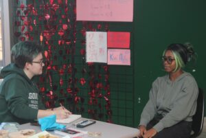 Kim Mullin (left) draws a caricature of Elizabeth Adeleke (right) at the illustration and concept art shop in J-building.