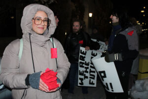 A protester holds red fabric squares distributed during the OSAP demonstration at the University of Ottawa. Students adopted the squares as a symbol of solidarity, visibility and support for accessible education, wearing them on jackets and coats throughout the march.