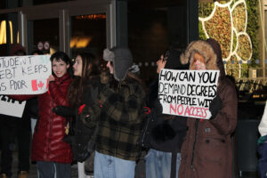 Students march through the University of Ottawa campus during an OSAP protest, holding signs calling attention to student debt and barriers to post-secondary access.