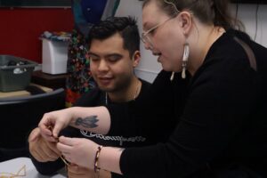 Ashley Clark helps student new to making dreamcatchers.