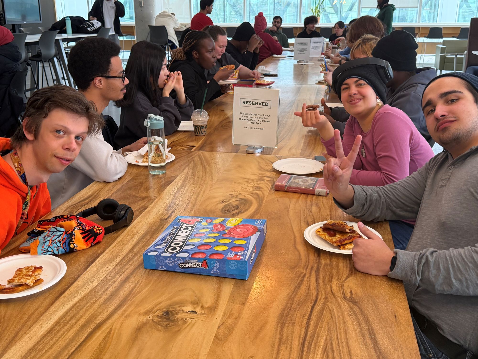 Students chat in groups with board games and pizza.