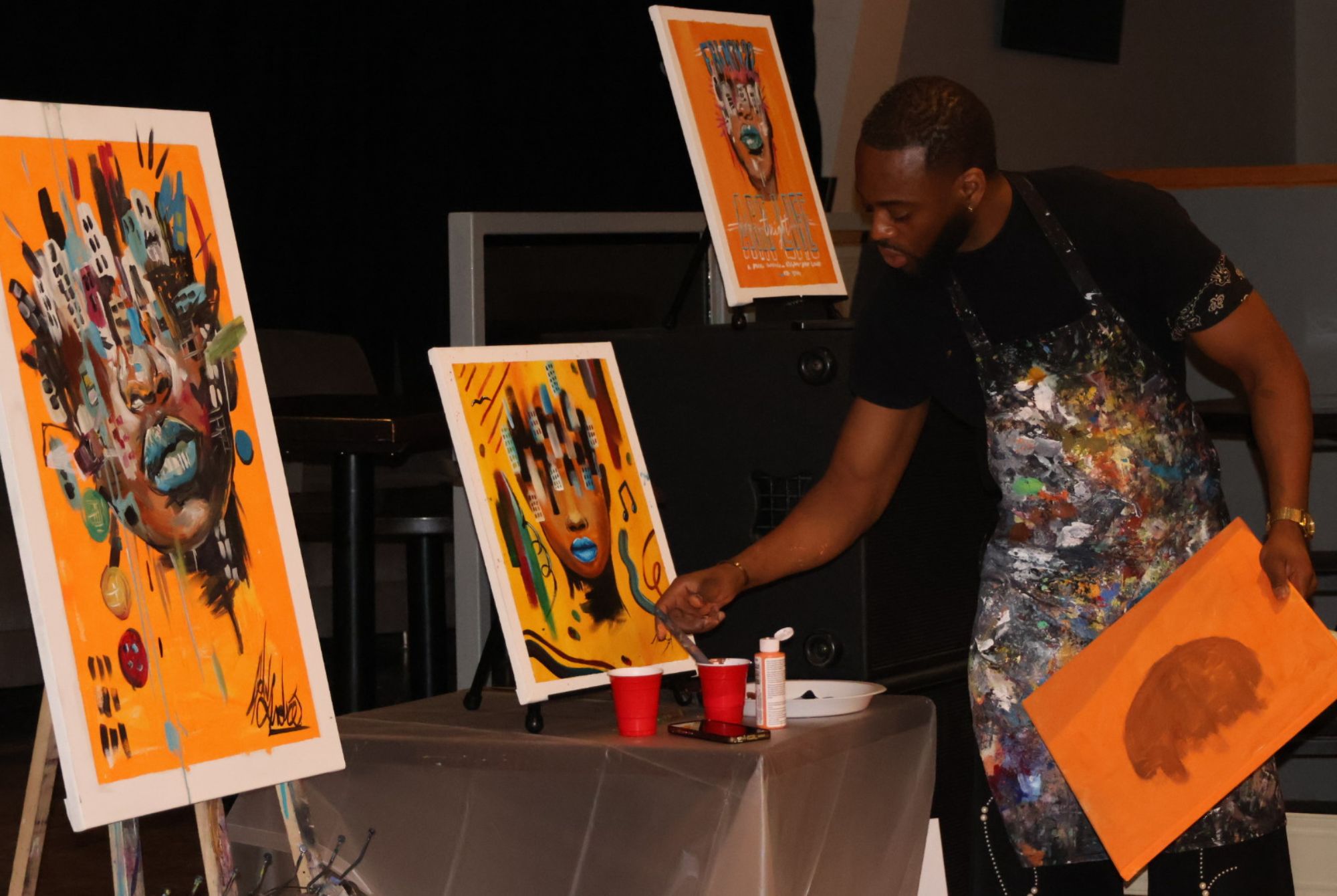 Allan André standing in front of his finished artwork while showing students how to recreate it.