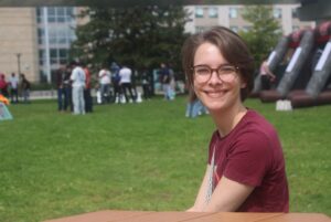 Marley Therrien sitting at a table in the front yard of the Student Commons during AC Day 1.