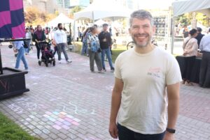 Chris Vickers stands in front of the interactive art zone where chalk drawings are dotted across the walkway.
