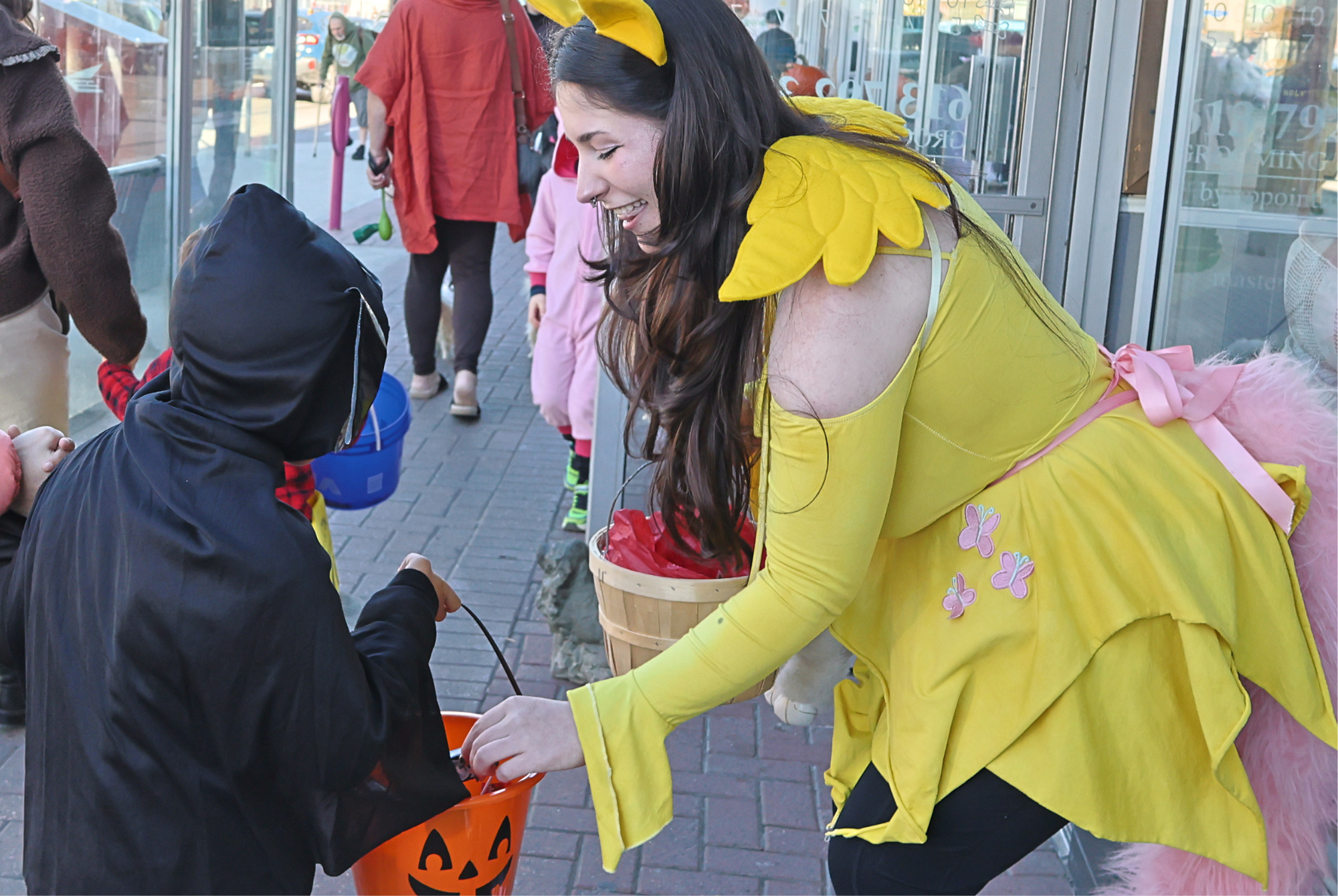 A woman dressed as a winged pony drops candy into a trick-or-treater's pumpkin pail outside a Richmond Road shop during Wickedly Westboro on Oct. 24.