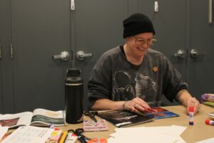 Linnea M. sitting at her collaging table during the event.