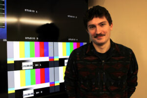 Noah Moors poses in front of equipment in Algonquin College's TV studio.