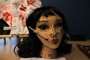 A mannequin head depicted with surgery lines and syringes.